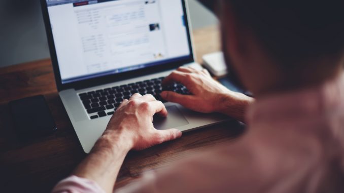 Cropped image of a young man working on his laptop in a coffee shop