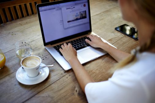 Back view of young successful female freelancer use net-book for distance work during her recreation time, woman's hands keyboarding on portable laptop computer with blank copy space on the screen