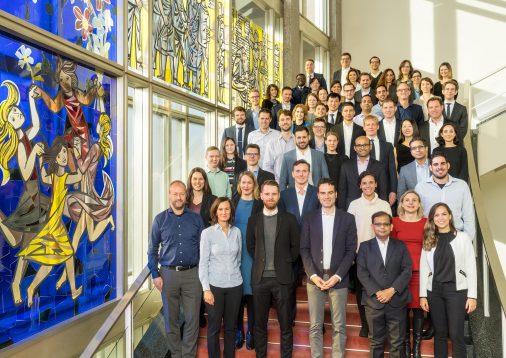 Executive MBA class of 2021 standing together in class photo on staircase at ESMT Berlin. 