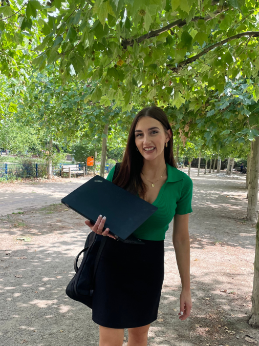 Female standing in front of a tree with laptop in hand