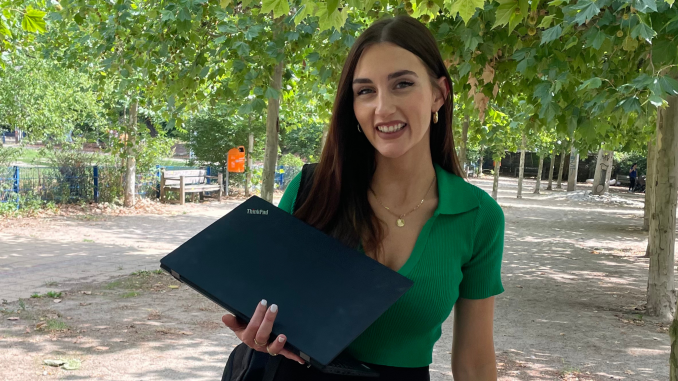 Female standing in front of a tree with laptop in hand