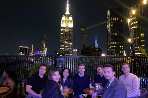 Group of interns having after work drinks with city skyline in background